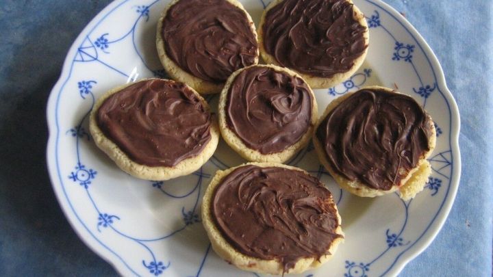 Sechs Marzipanberge auf einem Teller mit Schokoboden sind appetitlich angerichtet vor einem blauen Hintergrund.
