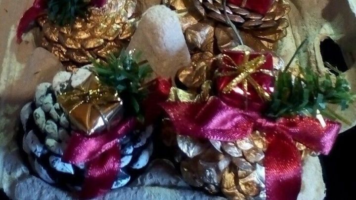 In einer Kartonverpackung stehen festliche, dekorierte Tannenzapfen, die Weihnachten repr&auml;sentieren und aufbewahrt werden.