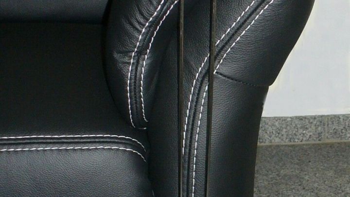 Ein schwarzes Sofa mit einem Kratzschutz, der an der Sofakante befestigt ist, um das Kratzen am Sofa unauff&auml;llig zu verhindern.