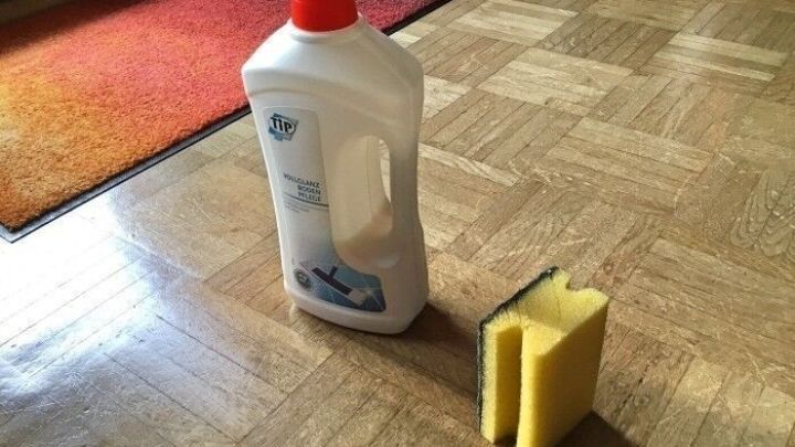 Ein Flaschenreiniger und ein Schwamm stehen auf einem Parkettboden, bereit, um Striemen effektiv zu entfernen.