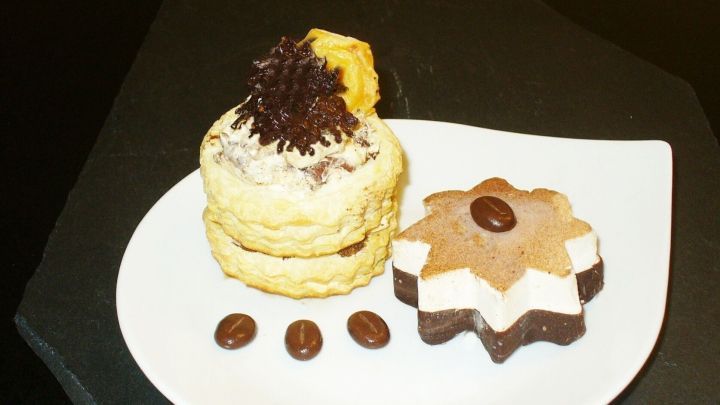 Zarte Bl&auml;tterteigpastete mit Mascarpone-F&uuml;llung und Apfelkompott, dekoriert mit Kaffeebohnen auf einem wei&szlig;en Teller.