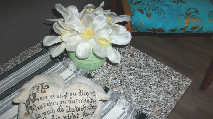 Eine Vase mit wei&szlig;en Tulpen steht auf einem gemusterten Tisch, umgeben von einem dekorativen Stein im Raum.