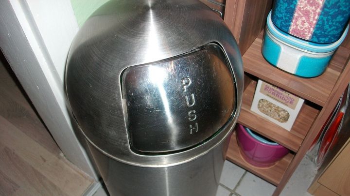 Ein M&uuml;lleimer aus Edelstahl steht in einem Raum und wartet darauf, M&uuml;ll durch das druckempfindliche &bdquo;PUSH&ldquo;-Fenster aufzunehmen.