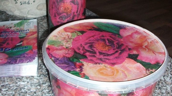 Bunte Dosen aus Plastikbeh&auml;ltern stehen auf einem Tisch, dekoriert mit bl&uuml;henden Rosen, bereit zum Basteln.