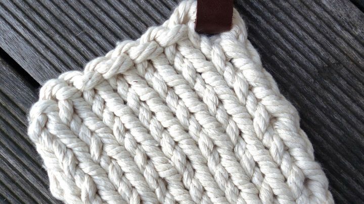 Ein handgefertigter Untersetzer aus einem Tau liegt auf einer Holzoberfl&auml;che und zeigt eine strukturierte, geflochtene Oberfl&auml;che.