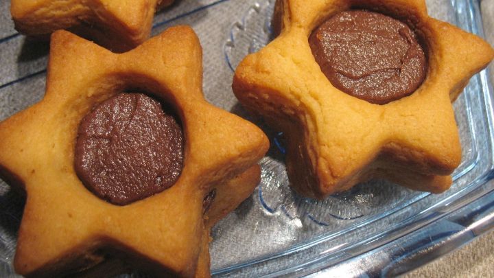 Zarte Butter-Doppelsterne liegen auf einer Glasplatte und sind mit schokoladiger F&uuml;llung in der Mitte versehen.