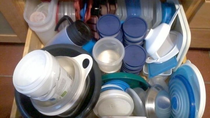 Der volle K&uuml;chenschrank enth&auml;lt alte Plastikbeh&auml;lter und Gegenst&auml;nde, die sortiert und weggeworfen werden sollten.