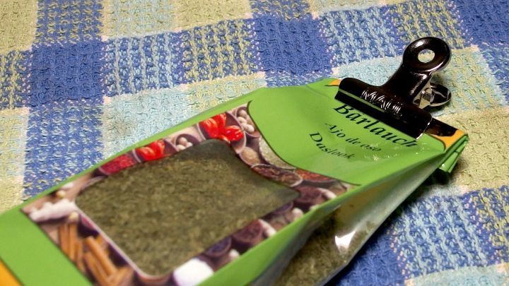 Eine T&uuml;te mit Kr&auml;utern wird durch eine Klammer perfekt verschlossen und liegt auf einem karierten Tuch.