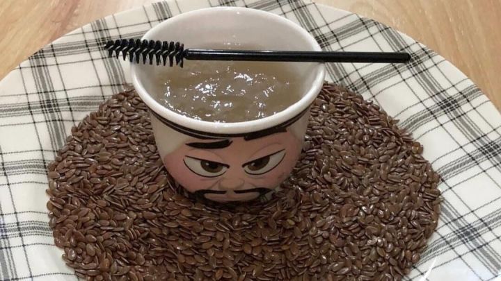 Eine Sch&uuml;ssel mit einem Haargel aus Leinsamen steht auf einem Teller, umgeben von geschroteten Leinsamen.