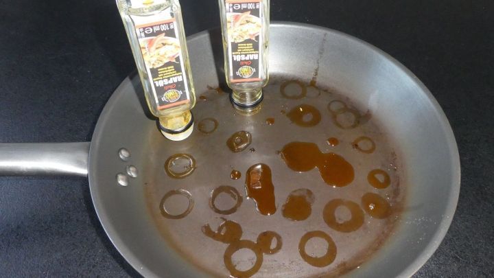 Eine Pfanne enth&auml;lt gebrauchten Speise&ouml;l, w&auml;hrend zwei fast leere Flaschen in ihr stehen und das &Ouml;l sammeln.