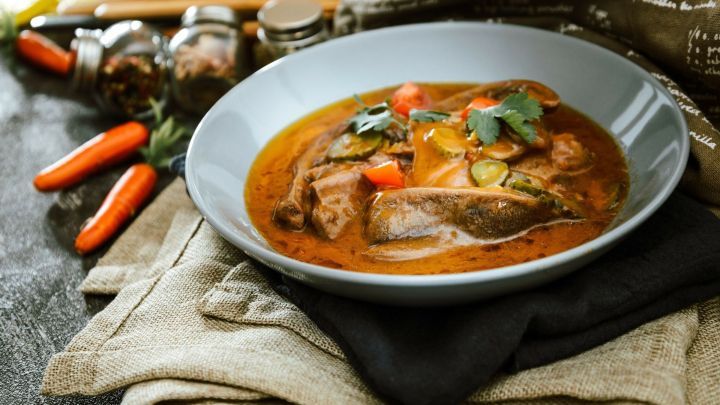 Rinderzunge liegt in einer w&uuml;rzigen Madeiraso&szlig;e, umgeben von frischen Kr&auml;utern und buntem Gem&uuml;se, serviert in einer stilvollen Schale.