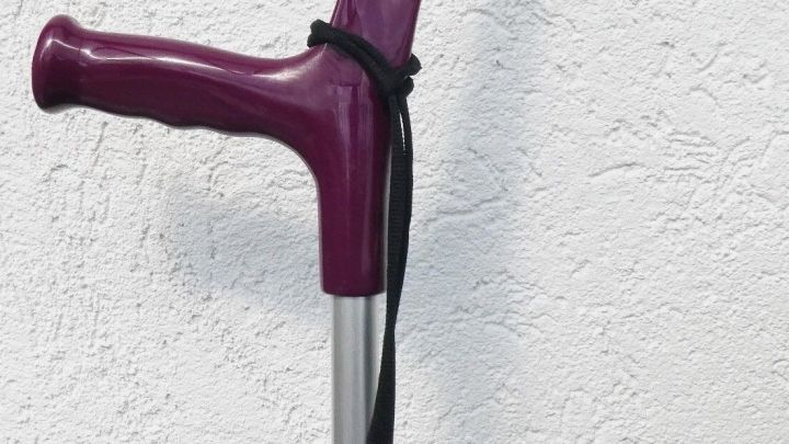 Eine lila Gehhilfe steht an einer wei&szlig;en Wand, bereit, beim Einkaufen Unterst&uuml;tzung zu bieten.