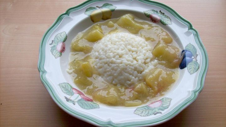 Eine Sch&uuml;ssel Rhabarber-Kaltschale mit Vanillereis. Der Reis liegt mittig in der fruchtigen Fl&uuml;ssigkeit, umgeben von frischen Rhabarberst&uuml;cken.