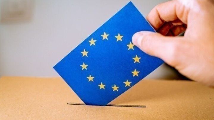 Eine Hand wirft einen Wahlzettel mit dem EU-Flaggenmotiv in einen Briefkasten, um an der Europawahl teilzunehmen.