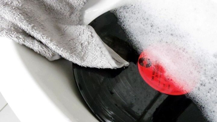 Eine Schallplatte wird mit einem Lappen in einer Seifenlauge gereinigt, um sie von Schmutz zu befreien.