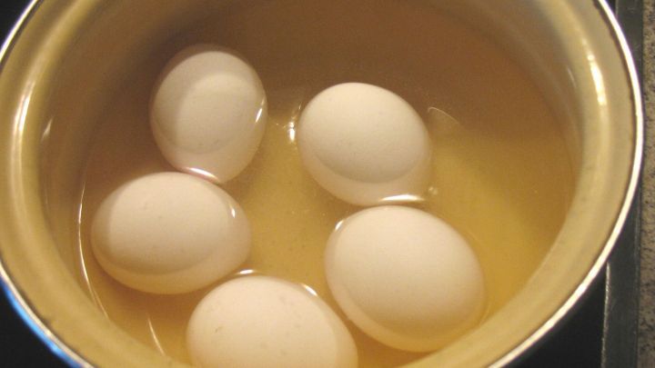 Wei&szlig;e Eier liegen in einem Kochtopf mit Wasser, bereit zum Kochen und sp&auml;teren leichten Sch&auml;len.
