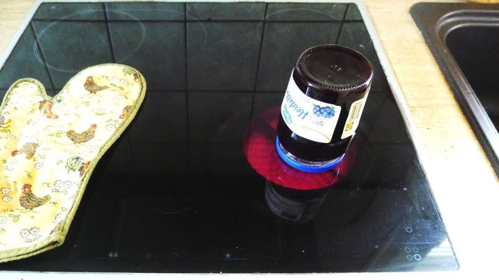 Eine Glasjarre steht auf einem Herd, w&auml;hrend ein Topflappen daneben liegt, um beim &Ouml;ffnen des Deckels zu helfen.