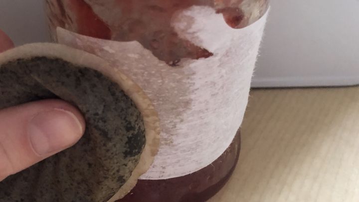 Ein Glas mit einem Etikett wird mit einem Schwamm gereinigt, um die Etikettenr&uuml;ckst&auml;nde zu entfernen.