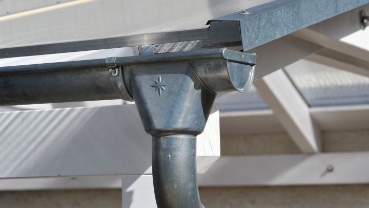 Ein verstopftes Fallrohr von der Dachrinne wird in einem modernen Haus gezeigt, das dringend freigemacht werden muss.