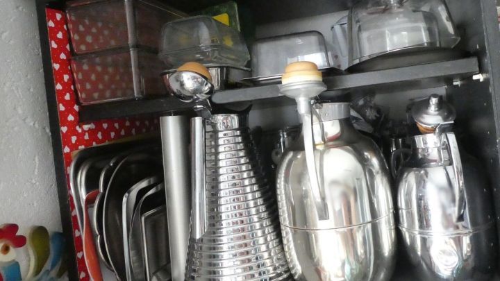 Ein Regal zeigt eine ordentliche Anordnung von K&uuml;chenutensilien und Aufbewahrungsboxen, um &Uuml;bersichtlichkeit zu bewahren.