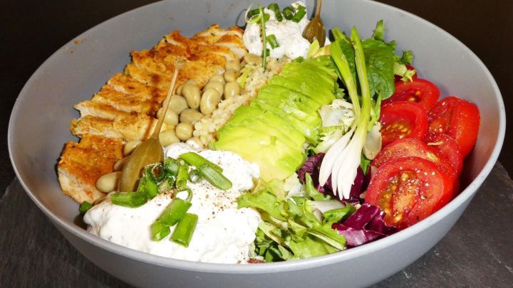 Ein Salat mit H&auml;hnchenbrust liegt in einer grauen Sch&uuml;ssel, bunt angereichert mit frischem Gem&uuml;se und Dressing.