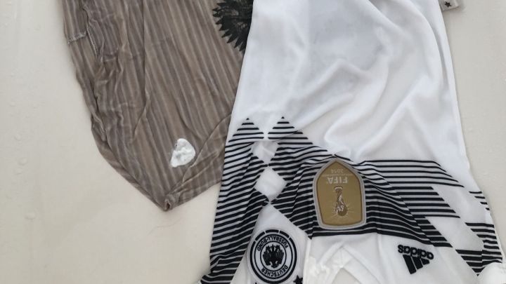 Zwei Kleidungsst&uuml;cke liegen nebeneinander auf einem hellen Untergrund, eines mit Flecken, das andere sauber, gleich daneben.