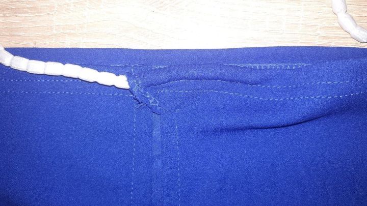 Ein blauer Bleistiftrock liegt flach auf einem Tisch, mit einem sichtbaren elastischen Bund, bereit zum Anziehen, ohne zu rutschen.