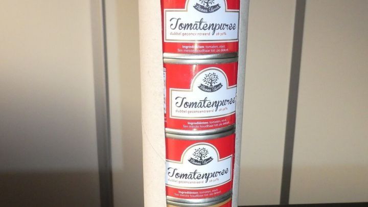 Kleine Dosen sind sicher und ordentlich gestapelt in einer hohen, stabilen Anordnung auf einem Tisch.