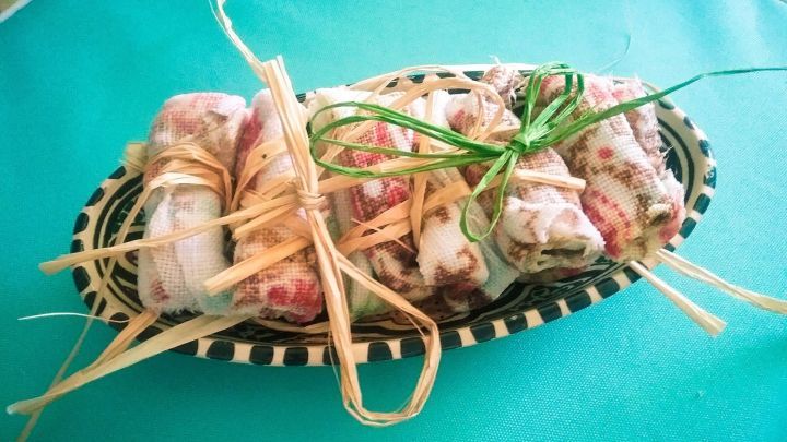 Auf einem Korb liegen frisch zubereitete Salbei-Minze Frost-T&uuml;chlein, liebevoll mit Kr&auml;utern gebunden und auf hellem Hintergrund pr&auml;sentiert.