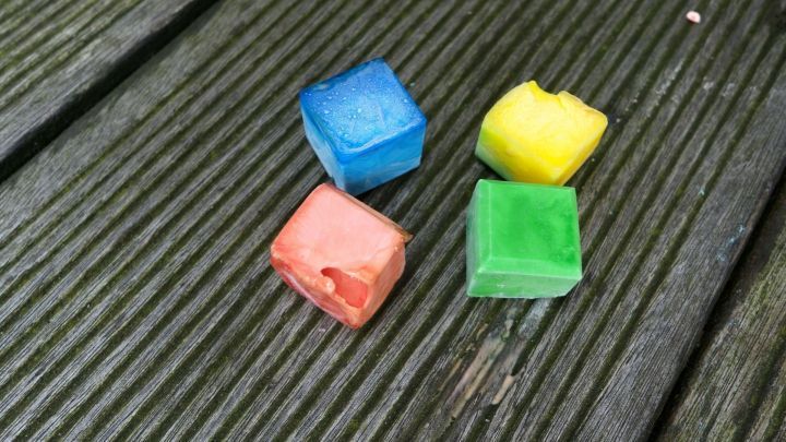 Bunte Eiskreidew&uuml;rfel liegen auf einer Holzoberfl&auml;che und warten darauf, im Sommer verwendet zu werden.
