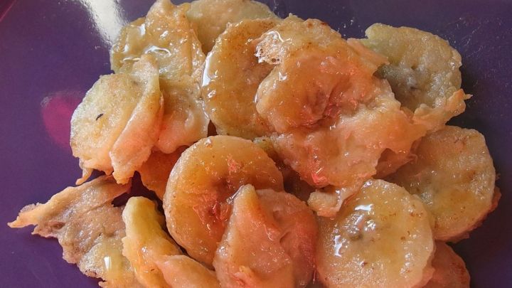 Gebackene Bananen liegen goldbraun auf einem lila Teller und verlangen nach einem k&ouml;stlichen Genusserlebnis.