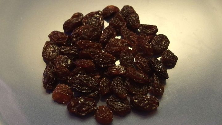 Dunkle Rosinen liegen auf einem hellen Teller, bereit zum Verteilen im Kuchen f&uuml;r eine leckere Ausgestaltung.