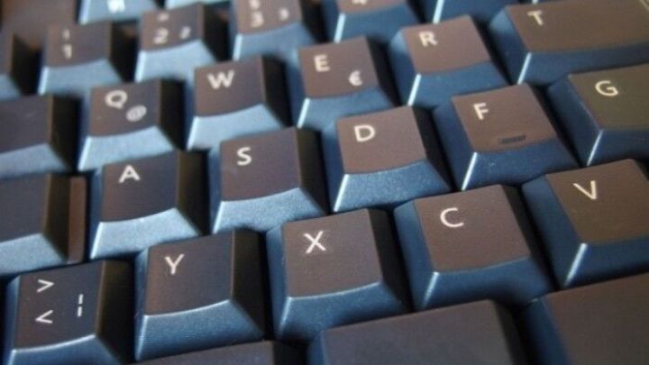 Eine dunkle Tastatur liegt vor einem unscharfen Hintergrund. Haarf&auml;rbepinsel wird verwendet, um die Tasten abzukehren.