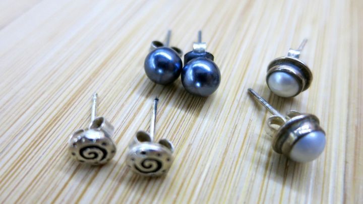 Zwei Paar Ohrstecker liegen auf einer Holzoberfl&auml;che, bereit zur praktischen Aufbewahrung oder Auswahl f&uuml;r den Tag.