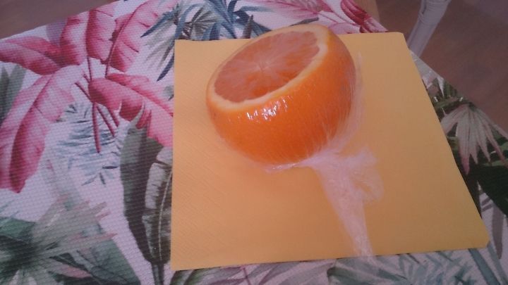 Eine angeschnittene Orange liegt auf einem gelben Teller, w&auml;hrend Saft herunterl&auml;uft; der Hintergrund zeigt ein blattartiges Muster.