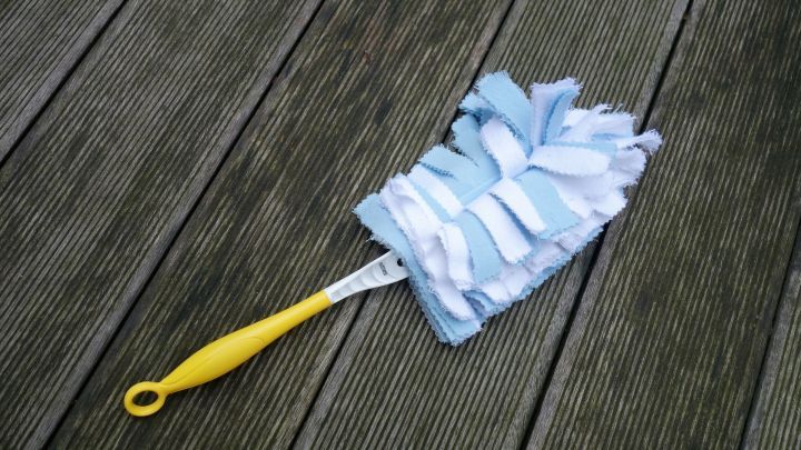 Ein waschbarer Staubwedel aus blauen und wei&szlig;en F&auml;den liegt auf einem Holzfu&szlig;boden, bereit zum Putzen.