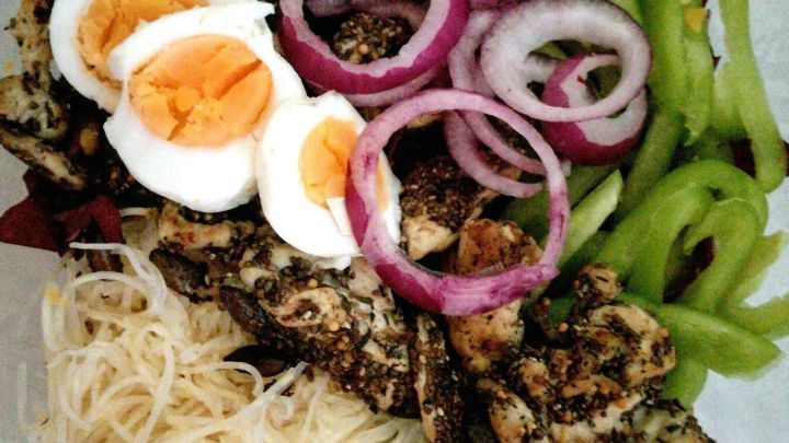 Ein bunter Salat aus Radicchio und Paprika mit Putenstreifen, hartgekochten Eiern und frischem Gem&uuml;se auf einem Teller.