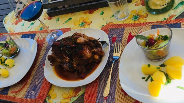 Zitronenh&auml;hnchen wird auf einem bunten Tisch serviert, umgeben von frischen Salaten und Getr&auml;nken.