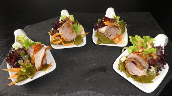 Auf vier wei&szlig;en L&ouml;ffeln sind thail&auml;ndische Filets angerichtet, umgeben von buntem Salat und einer Erdnussdip-Sauce.