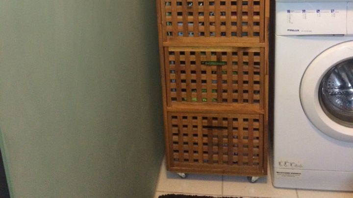 Ein Holzregal steht in einer Wohnung und wird genutzt, um W&auml;schek&ouml;rbe zu lagern und Nischen effizient zu nutzen.