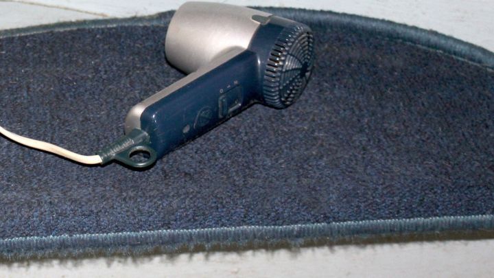 Ein F&ouml;n liegt auf einem Teppichbelag und wird verwendet, um diesen anzupassen und zu formen f&uuml;r eine bessere Passform.