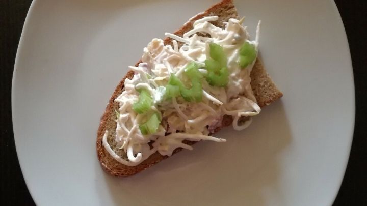 Ein belegtes Brot liegt auf einem wei&szlig;en Teller. Es ist mit einer cremigen R&auml;ucherforellenpaste und frischen Sojasprossen sowie Stangensellerie belegt.