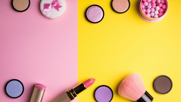Bunte Make-up-Produkte liegen auf einer geteilten Unterlage in Pink und Gelb, ideal f&uuml;r Make-up bei H&ouml;chsttemperaturen.