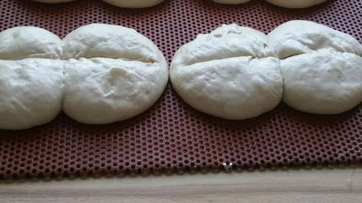 Teiglinge mit Wasser einspr&uuml;hen und mit einem scharfen Messer einschneiden.   In der Zwischenzeit Backofen vorheizen auf 230 &deg;Ober und Unterhitze, ganz unten die Fettpfanne mit vorheizen.