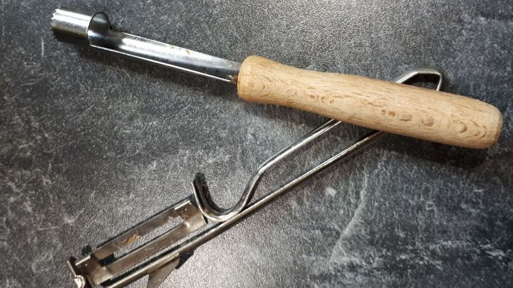 Ein K&uuml;chenhelfer mit Holzgriff liegt auf einer glatten, dunklen Oberfl&auml;che, bereit zum Reinigen mit Backpulver.