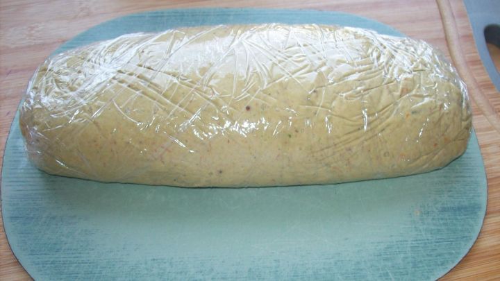 Die Pilzbutter ist als l&auml;nglicher, in Frischhaltefolie gewickelter Block auf einer blauen Unterlage zu sehen.