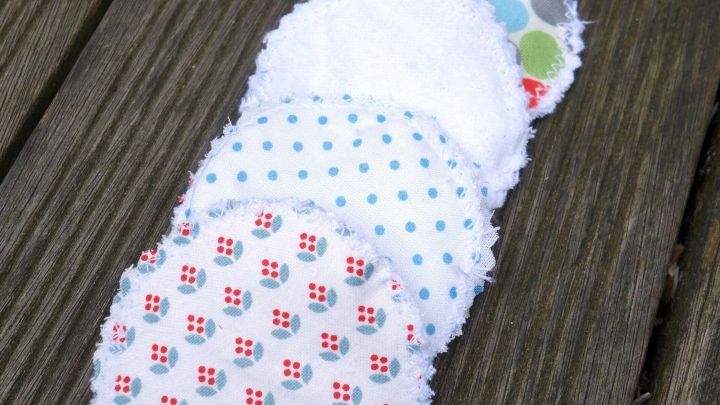 Runde, waschbare Kosmetikpads liegen auf einem Holztisch, farbenfroh gestaltet mit verschiedenen Mustern und Texturen.