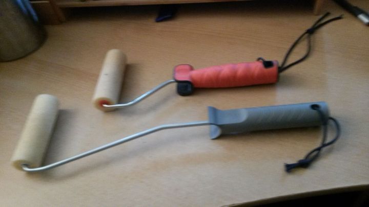 Zwei Malerrollen mit Griffen liegen auf einem Tisch, bereit zum Eincremen von R&uuml;cken und F&uuml;&szlig;en.