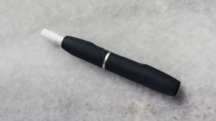Ein schwarzer IQOS-Stift liegt auf einer grauen Oberfl&auml;che und wartet darauf, gereinigt zu werden.