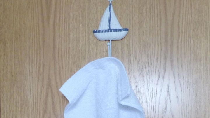 Ein handtuch h&auml;ngt an einer T&uuml;r, umgeben von einer einfachen Holzoberfl&auml;che, was einen angenehmen Duft im Badezimmer vermittelt.